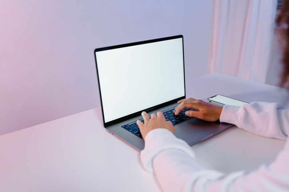 How to Set Up WireGuard VPN for Faster Mobile Connections Hands typing on a laptop with a blank screen on a white desk, smartphone nearby.