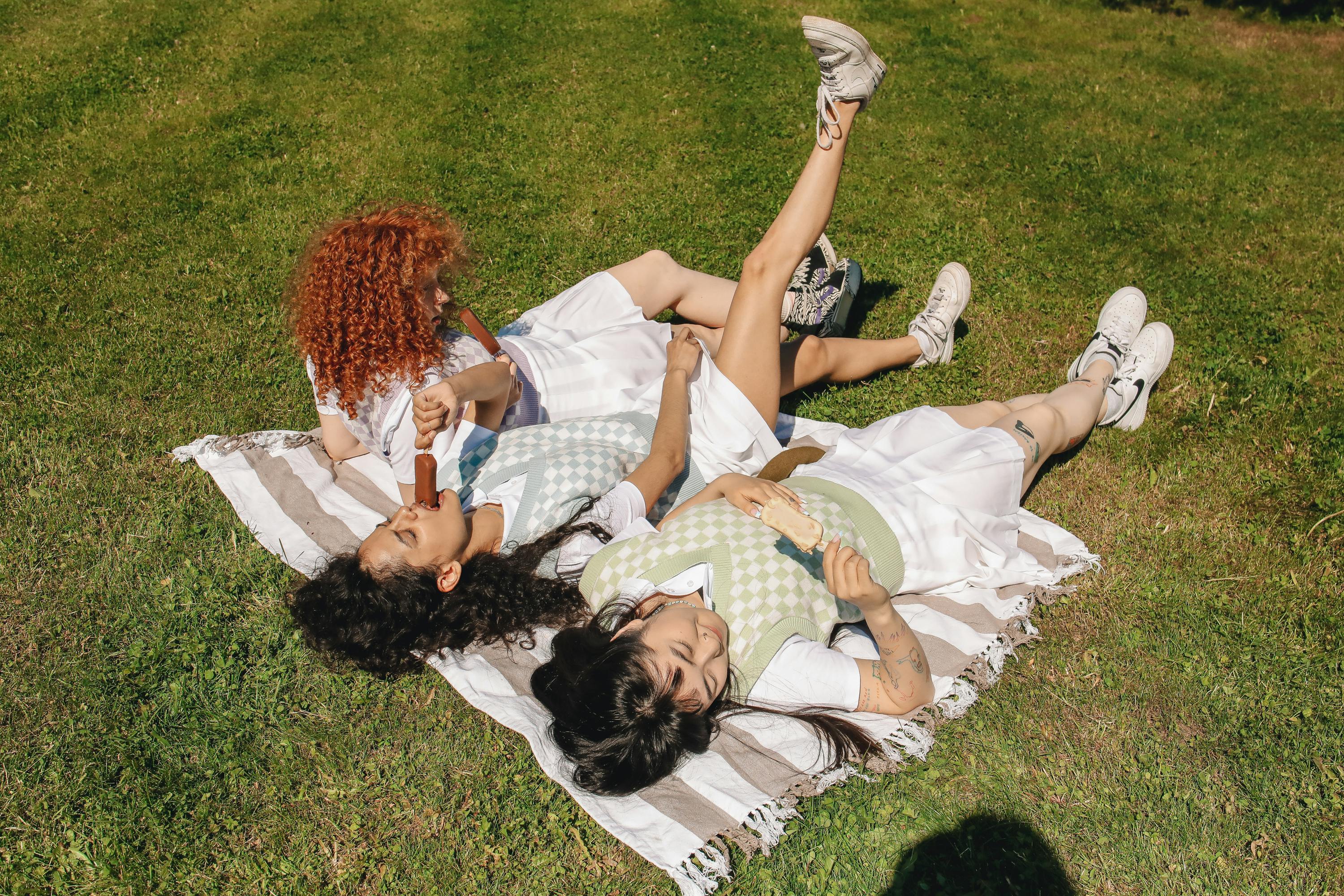 high angle shot of three girls lying on picnic blanket