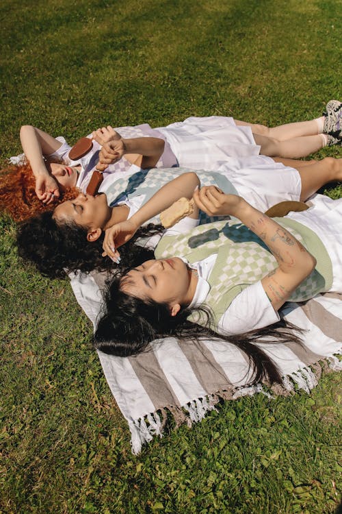 Women Lying on the Grass While Eating Ice Cream