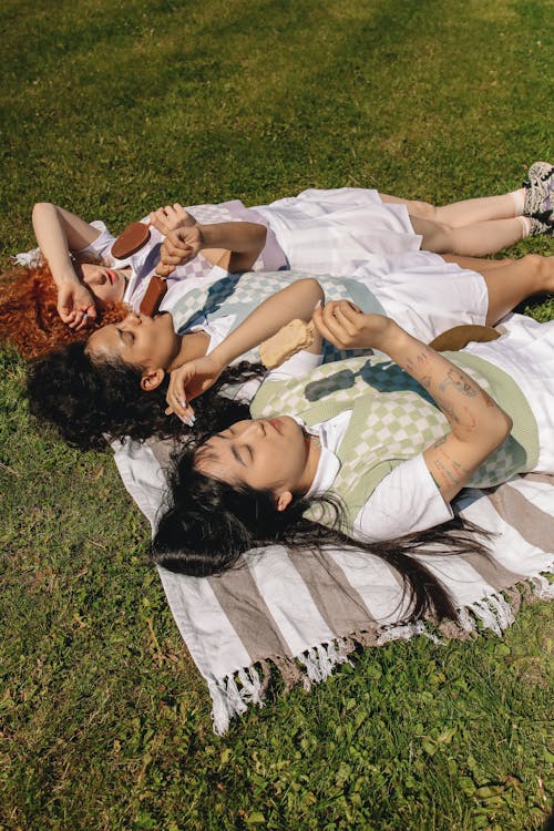 Women Lying on the Grass While Eating Ice Cream