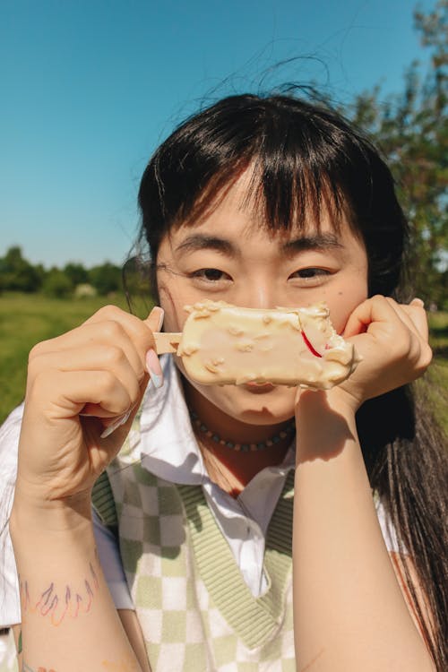 Woman in Green Sweater Vest Holding a Popsicle Ice Cream