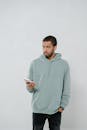 Man in Gray Hoodie Holding a Mobile Phone