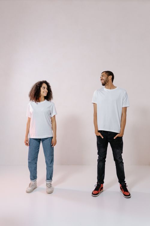 Free A man and woman wearing white shirts stand smiling in a bright studio. Stock Photo