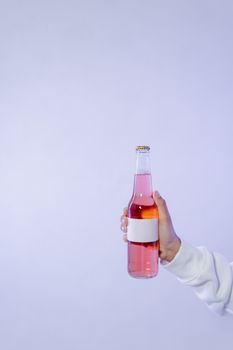 A minimalist studio shot of a hand holding a glass bottle with a blank label, perfect for product mockups.
