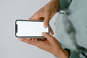 Hand holding a phone with a blank screen — photo by Mart Production on Pexels