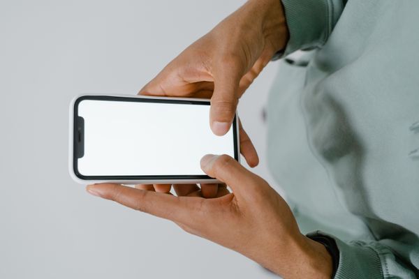 Hands holding a smartphone with a blank screen — photo by MART PRODUCTION on Pexels