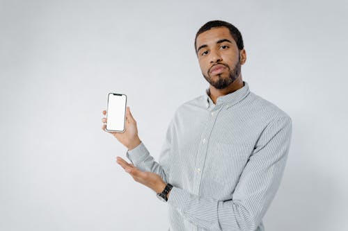 Photo of a Man in a Striped Shirt Holding a Cell Phone