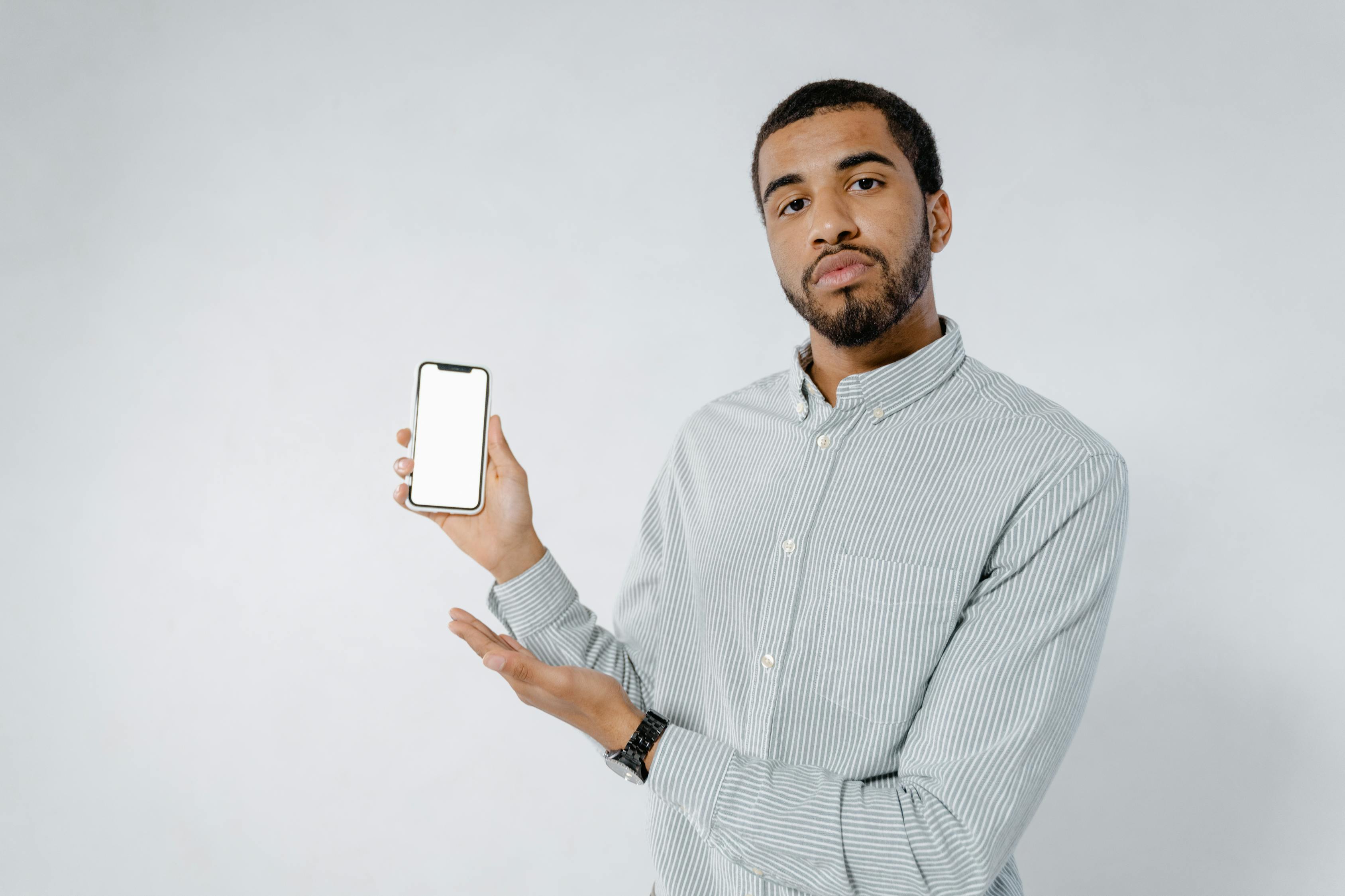 Man in White and Black Pinstripe Dress Shirt Holding White Smartphone