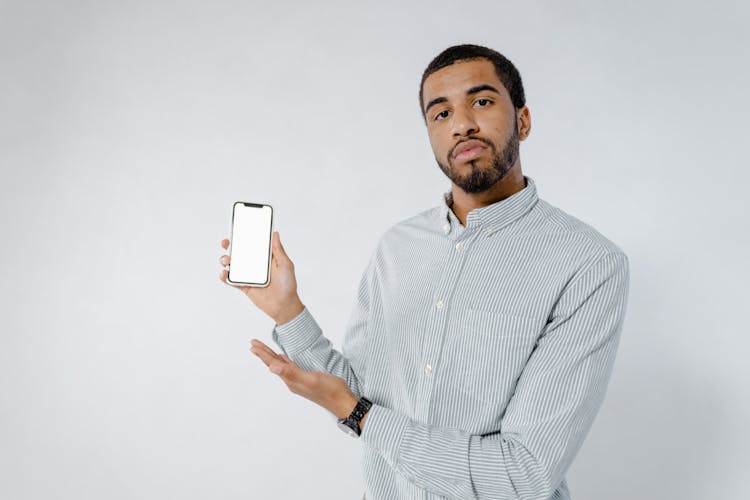 Photo Of A Man In A Striped Shirt Holding A Cell Phone