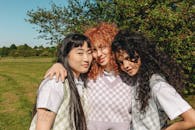 三名年轻女子在阳光明媚的日子里在户外拥抱并微笑