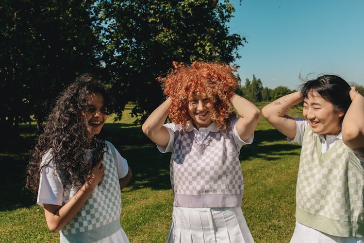 Three Young Women Laughing On Grass Field