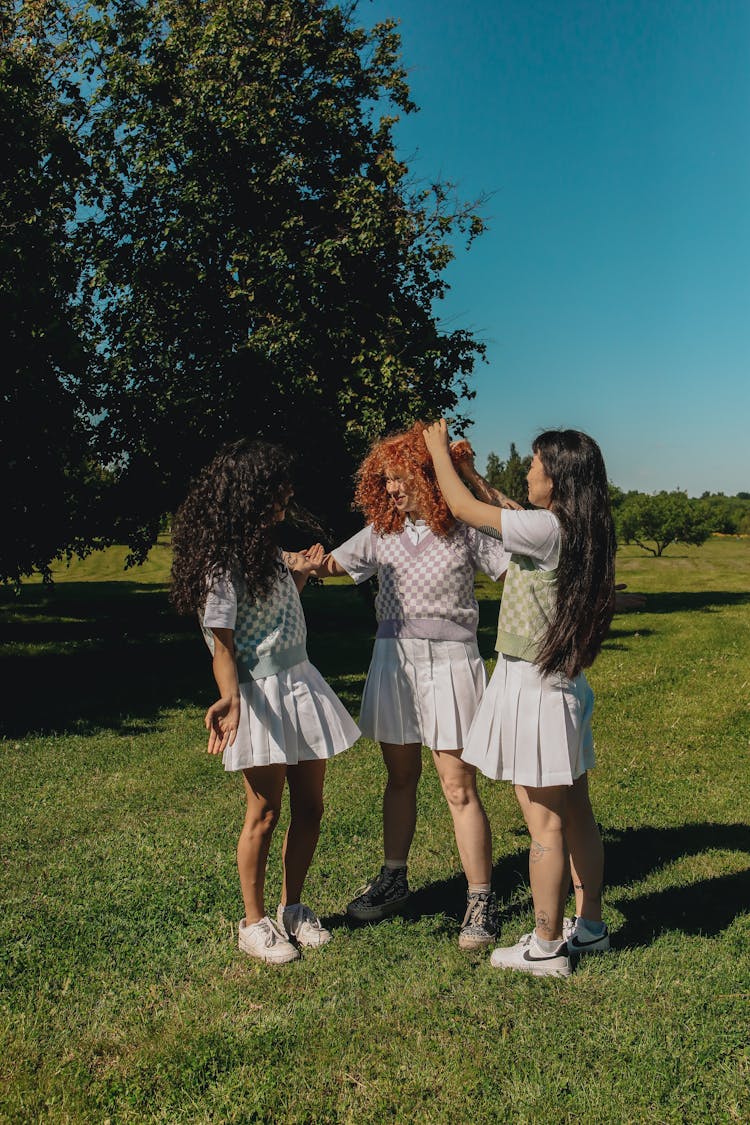 Teenage Girls Standing On Green Grass Field