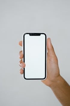 A minimalist mockup of a hand holding a smartphone with a blank screen.