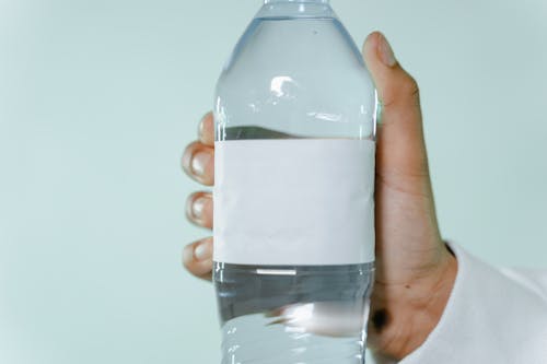 Free A Person Holding a Water Bottle with a Blank Label Stock Photo