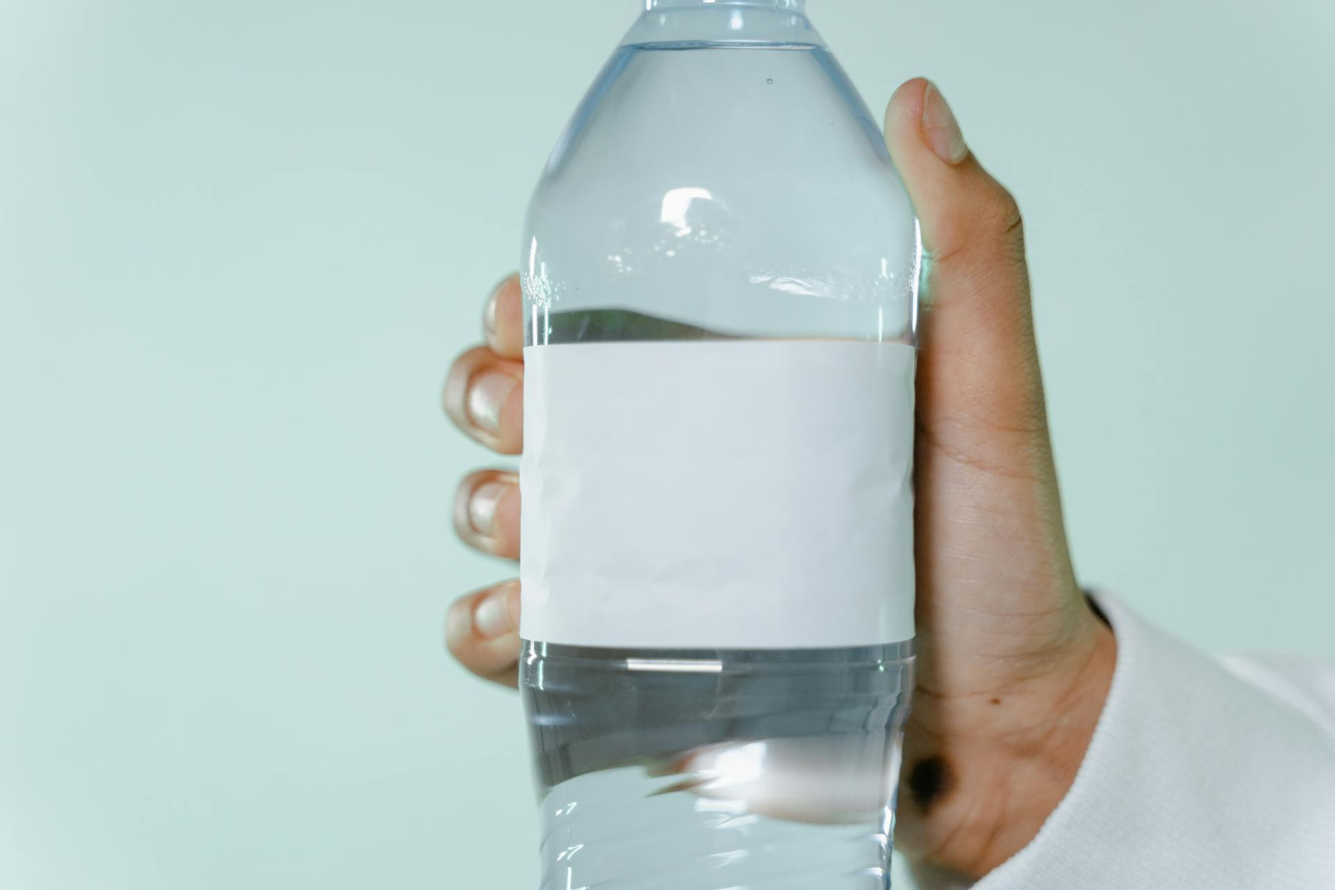 A Person Holding a Water Bottle with a Blank Label