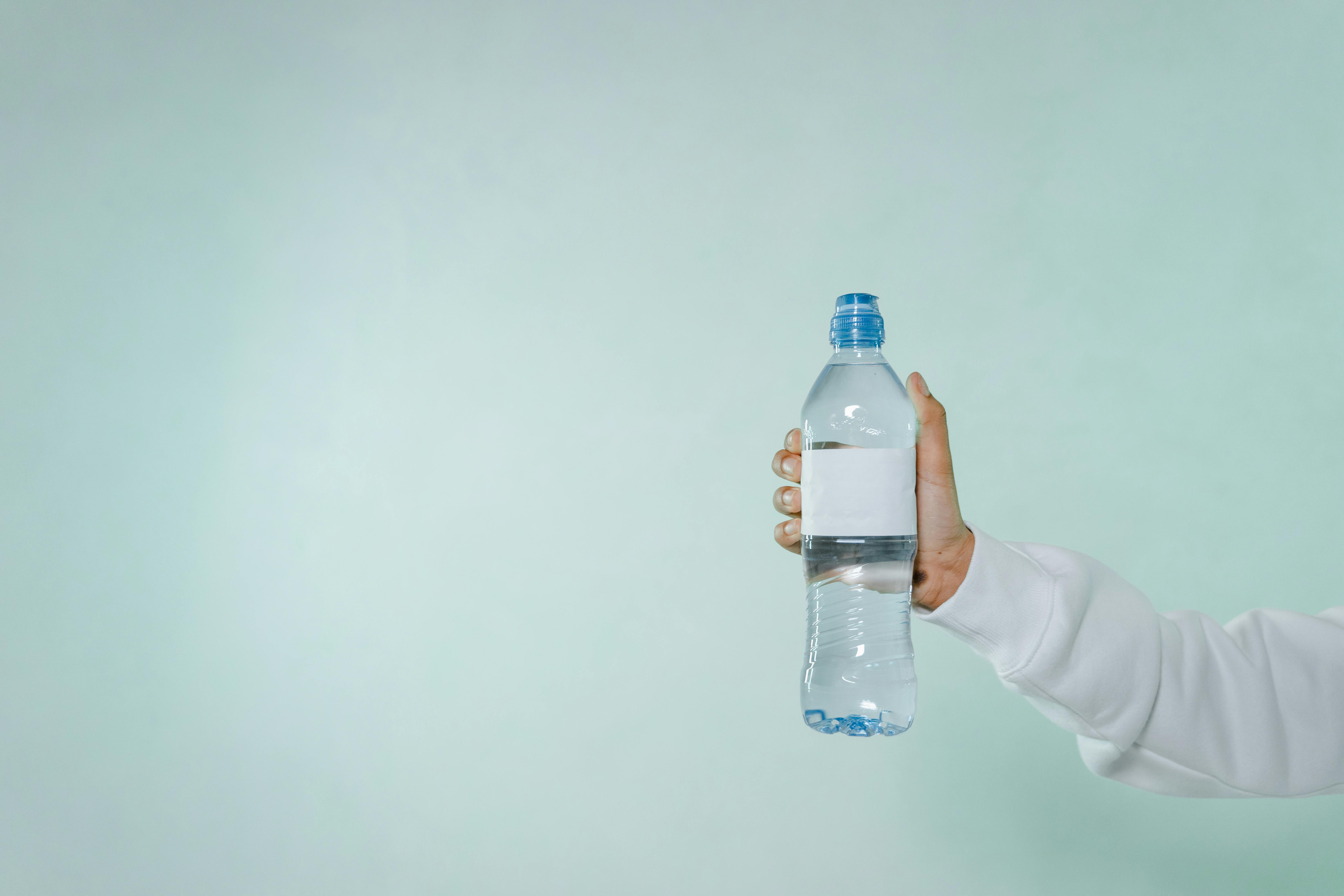 Photo of a Person's Hand Holding a Glass Bottle with Water · Free Stock  Photo