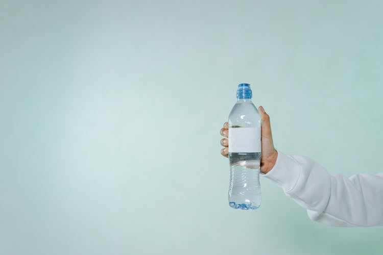 Photo Of A Person's Hand Holding A Bottle Of Water