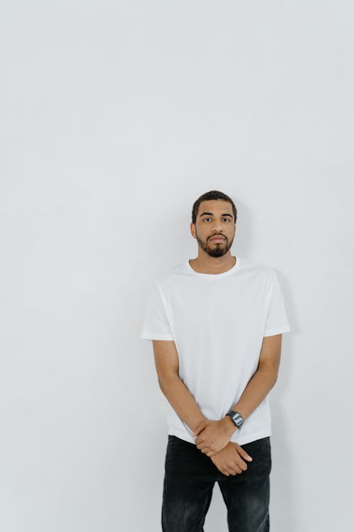 Man in White Shirt Standing Beside a White Wall