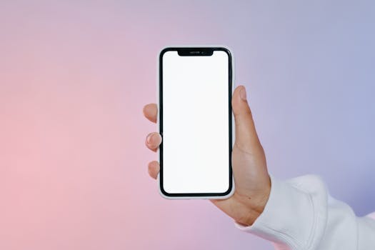 Close-up of a hand holding a smartphone with a blank screen against a colorful gradient backdrop.