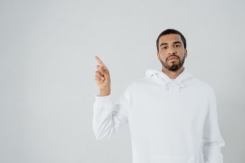 Free Adult male standing and pointing, wearing a white hoodie with a plain white background. Stock Photo