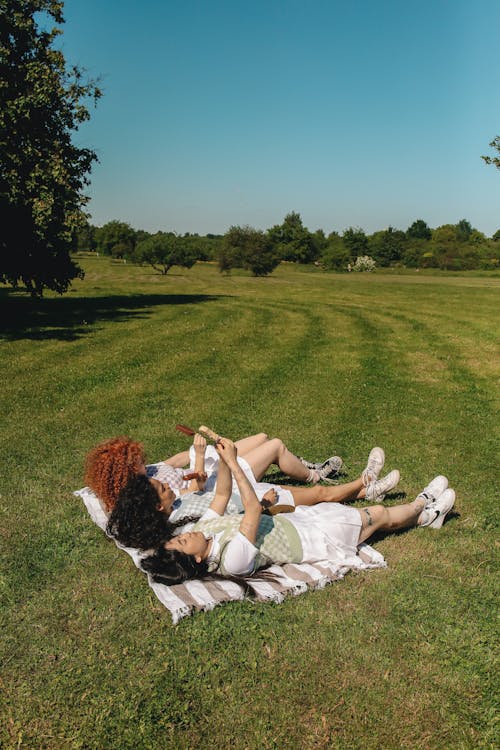 Photo of a Group of Girls Lying on a Blanket on a Field