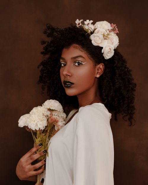 Free Elegant portrait of a woman holding flowers, showcasing beauty and style. Stock Photo