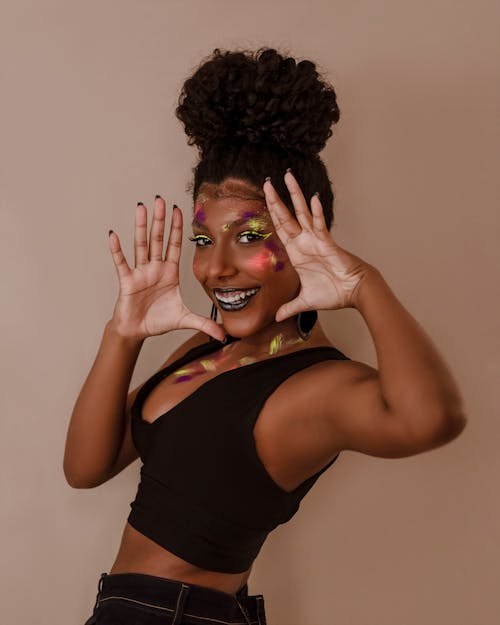 Photo of a Woman with Face Paint Posing with Her Hands Open