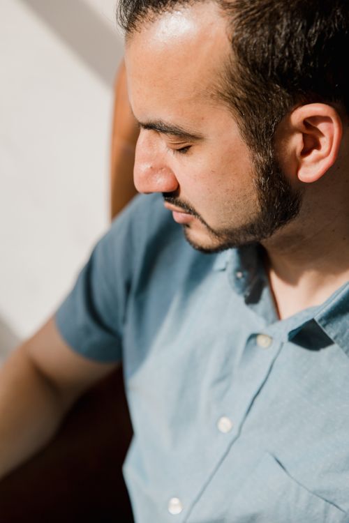 Free A serene portrait of a man with a beard in soft daylight, captured indoors. Stock Photo