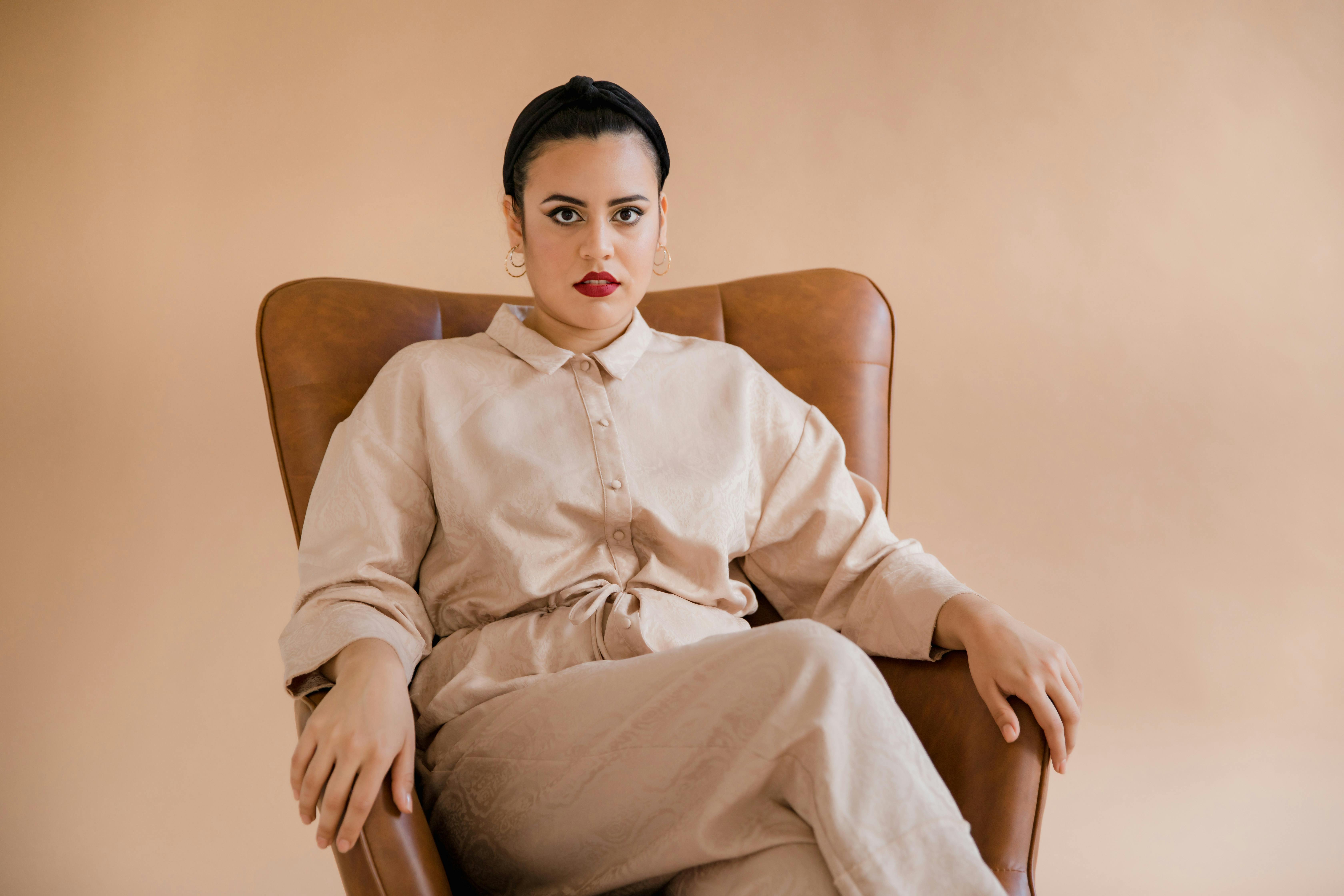 Woman in White Dress Shirt Sitting on Brown Chair