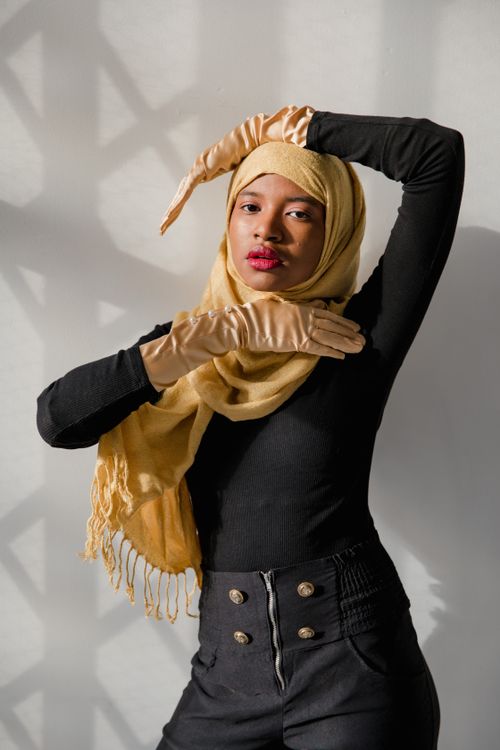 Free Elegant woman in a yellow hijab striking a pose with dramatic shadows indoors. Stock Photo