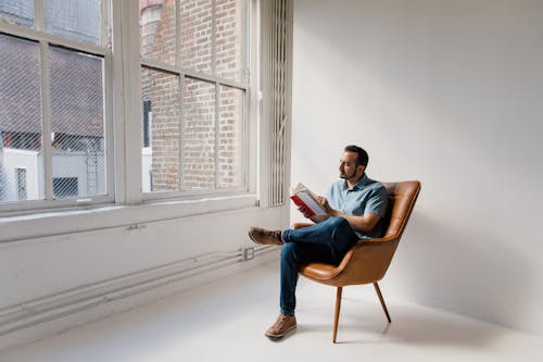 Man in Blue Dress Shirt Sitting on Brown Chair