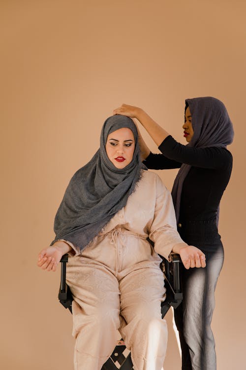 Woman in Black Long Sleeve Top Fixing Another Woman's Hijab