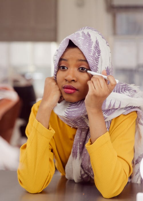 Woman in Yellow Long Sleeve Shirt Putting on Make Up