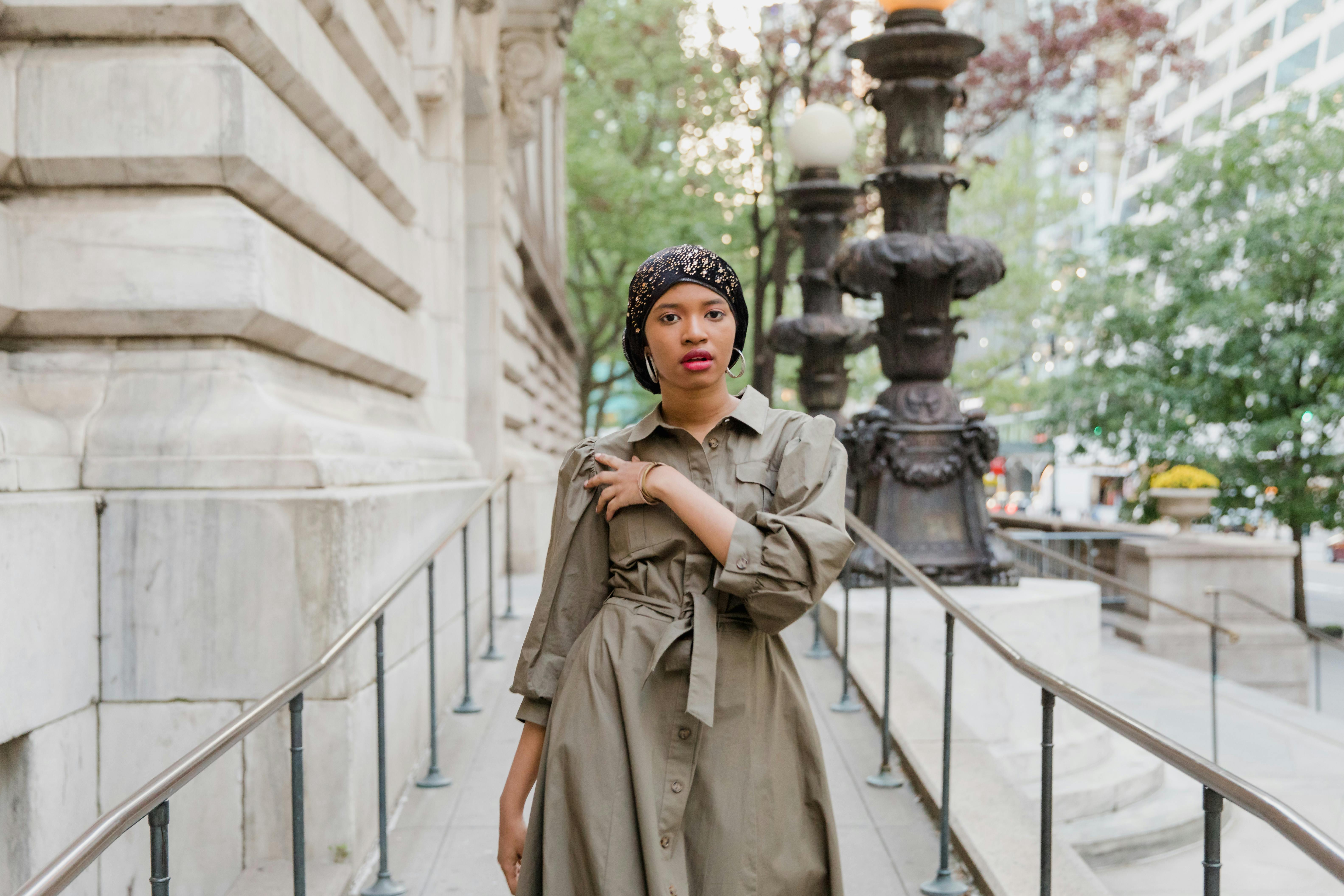 Woman in Brown Coat Standing on White Concrete Staircase