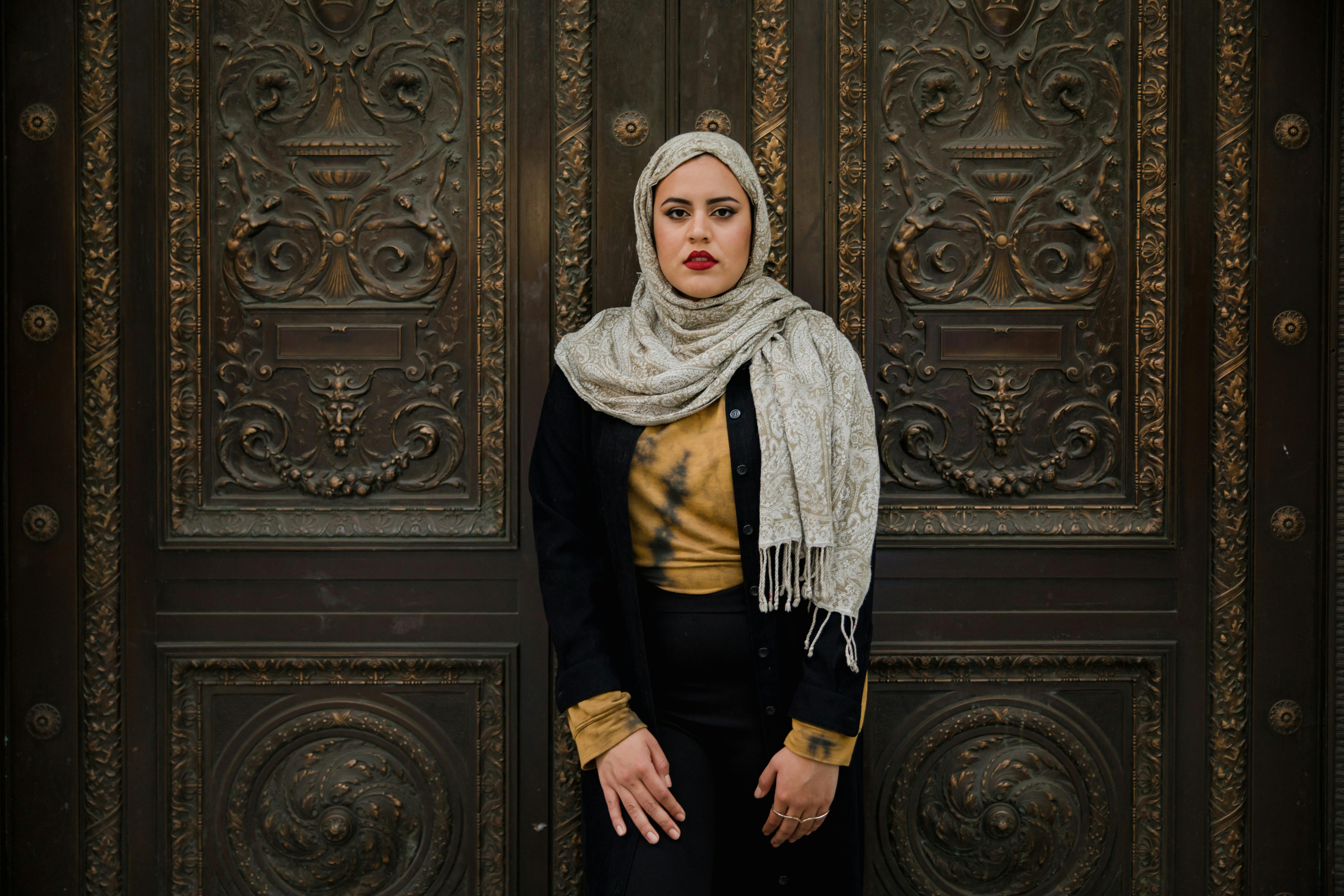 woman in black long sleeve shirt and hijab standing beside a door