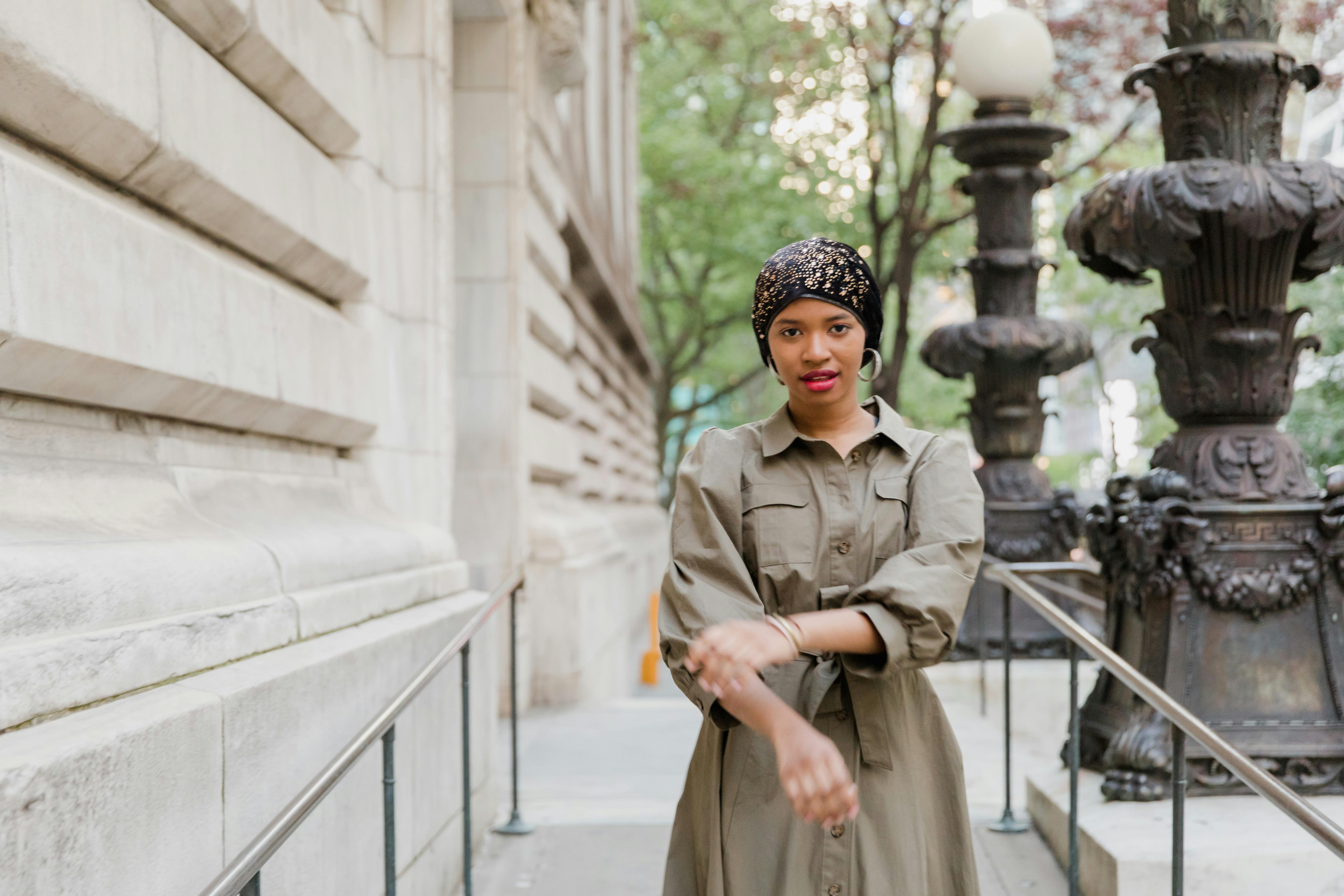 Woman in Brown Coat Standing Near White Concrete Building