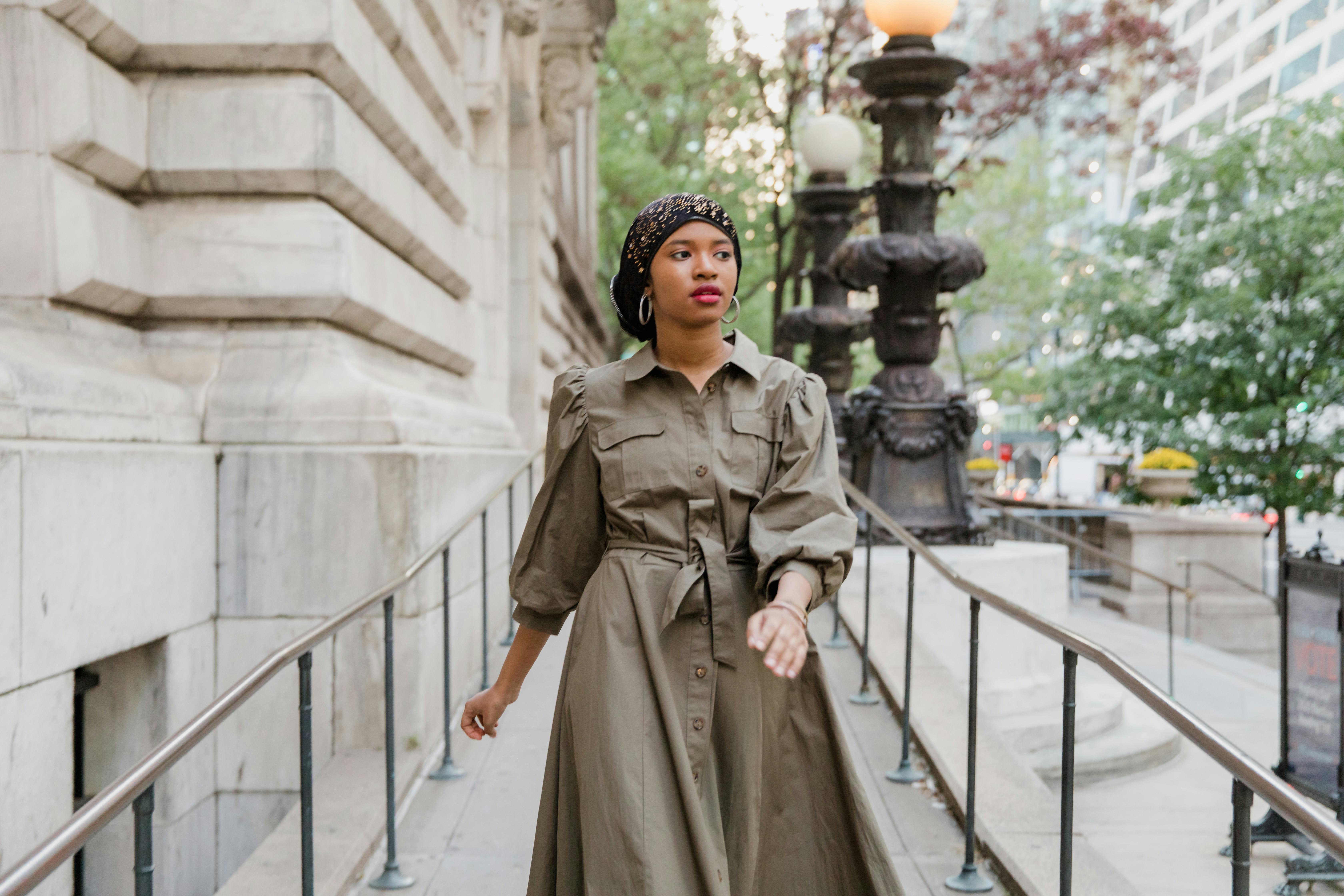 Woman in Brown Coat Standing on White Metal Bridge