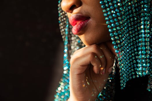 Close-up portrait of a person with blue beads and vibrant red lips, showcasing elegance and creativity.