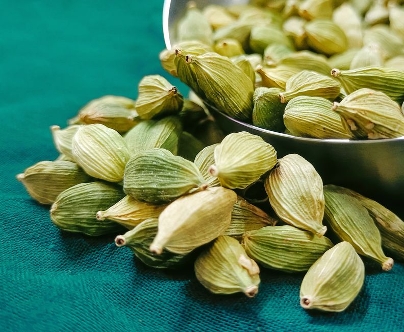 Semillas de cardamomo verde y negra en recipiente de vidrio