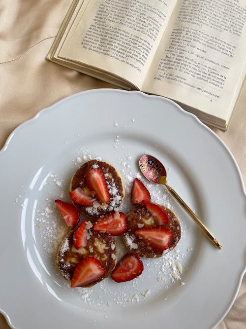 Overhead Shot of a Plate with Pancakes and Strawberries Near a Book