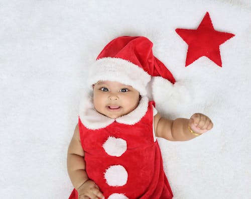 A Baby in Red Santa Hat Lying on the Bed
