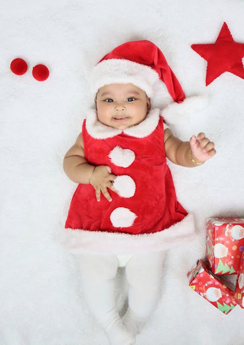 Photo of a Baby in a Santa Claus Costume Lying on a White Surface