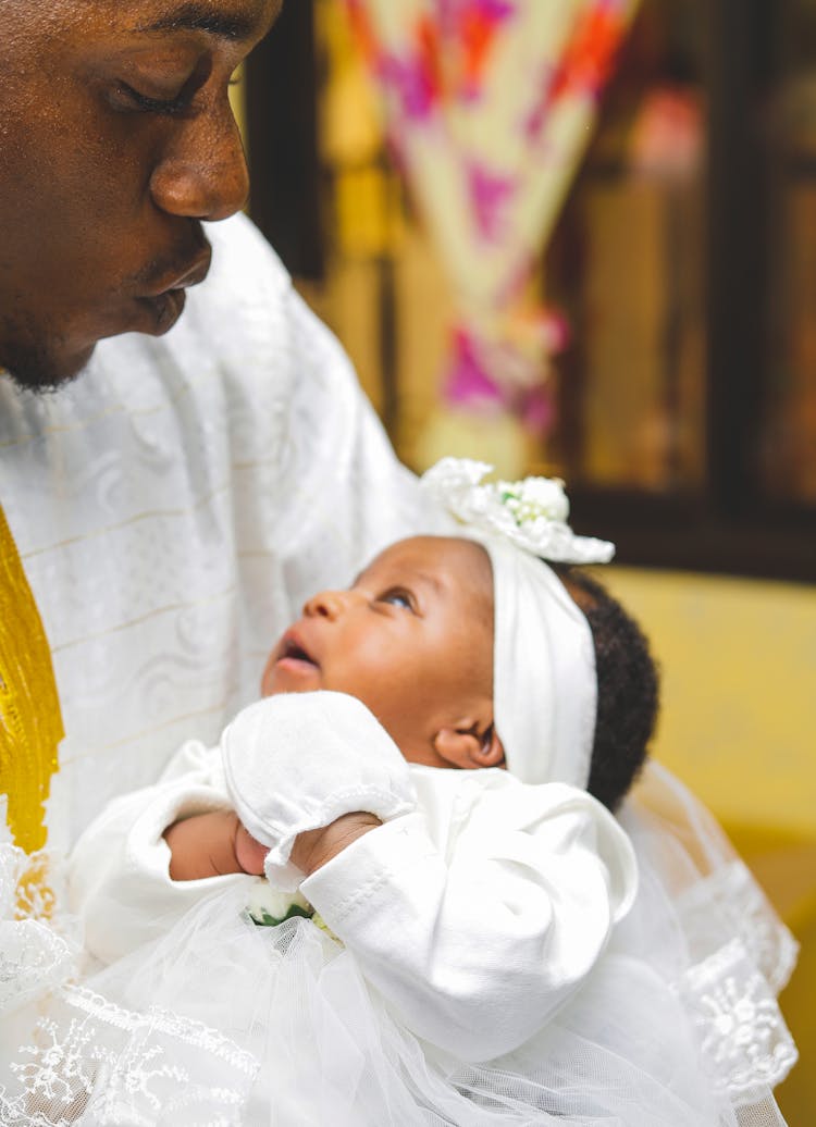 Photo Of A Man In A White Shirt Carrying A Baby