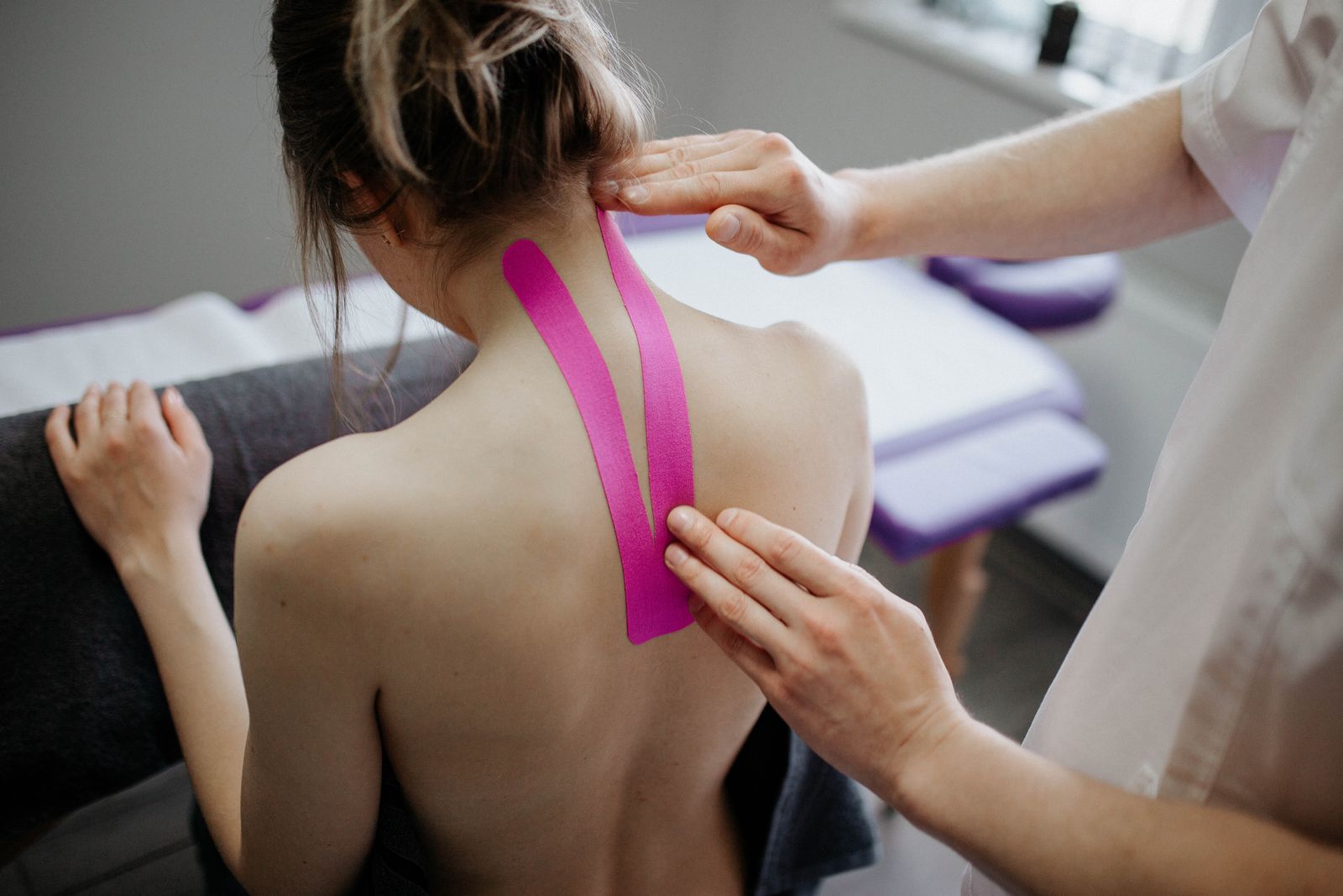 Bright close-up of a person touching the side of the neck while seated indoors