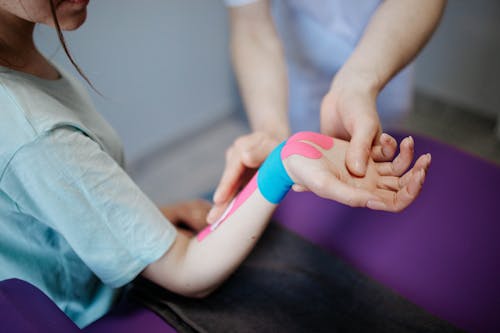 Free Person Applying Kinesio Tape On A Girl's Arm and Wrist Stock Photo
