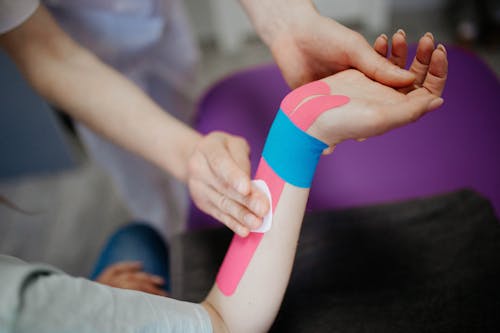 Free A Person Putting Kinesio Tape on Client's Arm Stock Photo