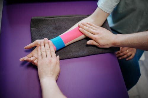 Free A Person Putting Kinesio Tape on another Person Stock Photo