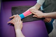 A Person Putting Kinesio Tape on another Person