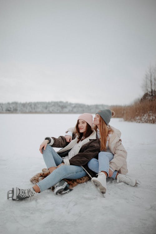 Women Sitting on Ice and Wearing Ice Skates