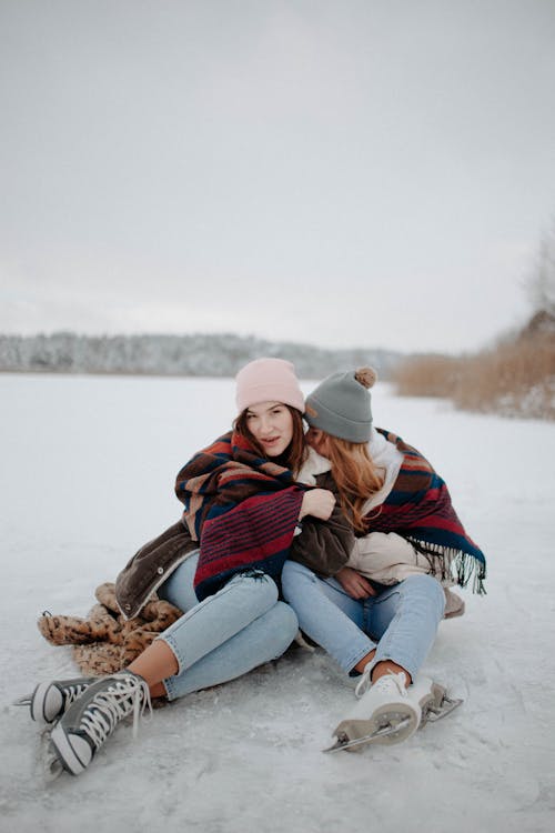 Two Women Sitting On Snow Covered Ground In Winter Clothes With Scarf ·  Free Stock Photo